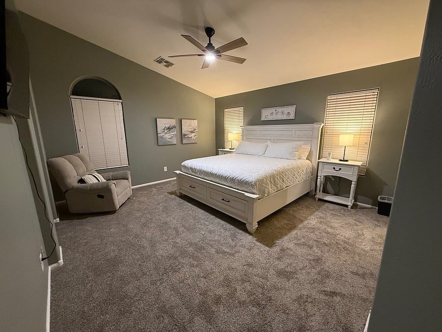 Spacious bedroom with vaulted ceiling, ceiling fan and reading chair in the Maricopa AZ monthly rental